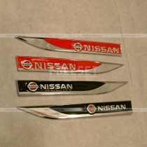 Металлические эмблемы в крыло на черном и красном фоне с надписью Nissan