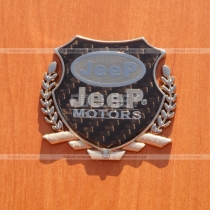 Эмблема Jeep с хромированным гербом на карбоновом фоне